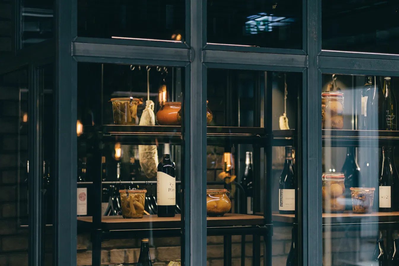 Regal der Schmitte mit Weinen und Eingemachtem hinter Glas und Stahl